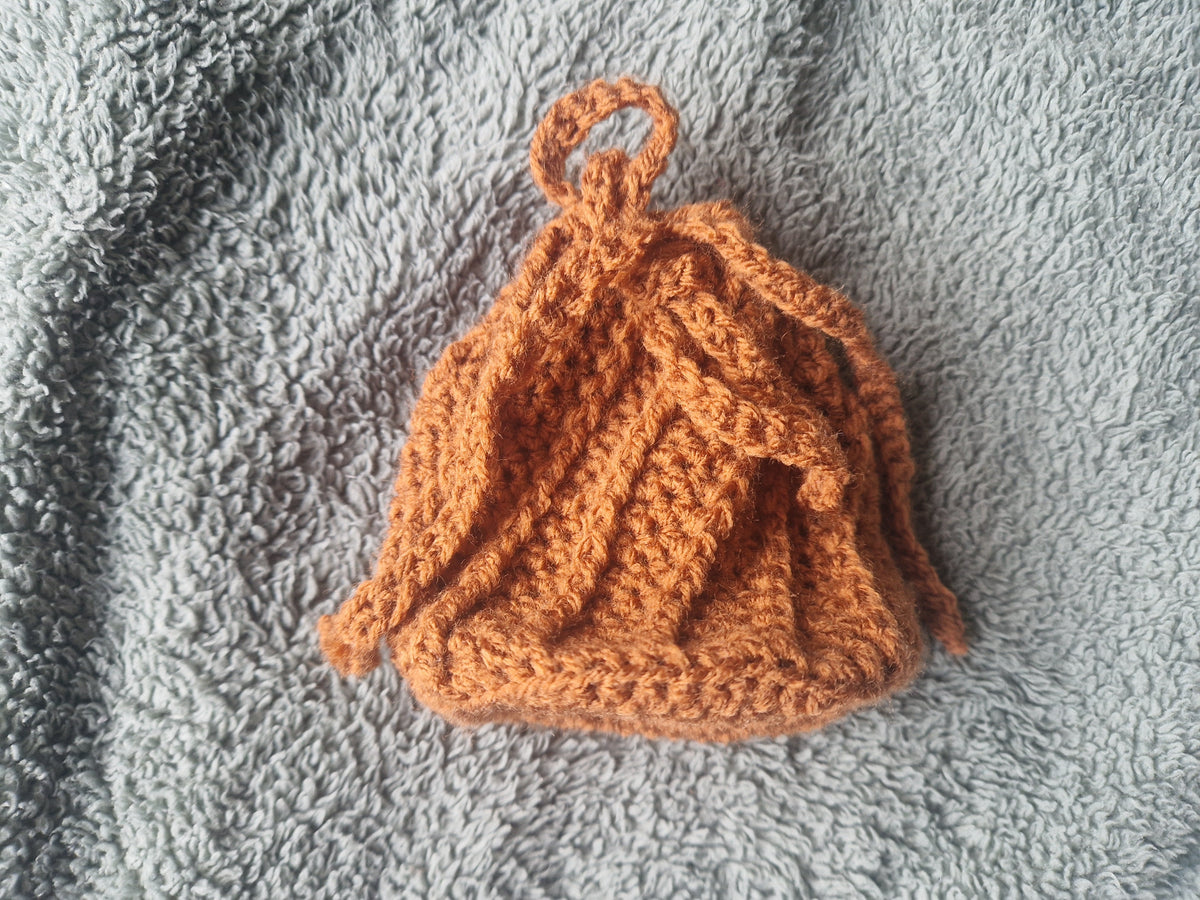 Brown crochet pouch on a gray textured surface